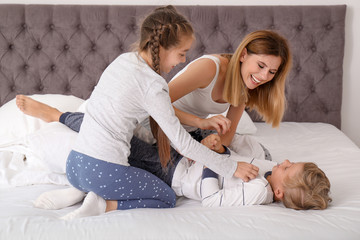 Canvas Print - Woman playing with children in bedroom. Happy family