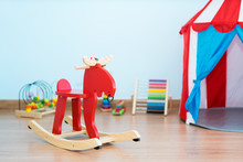 Red Rocking Deer Near Toy In Baby Room At House.