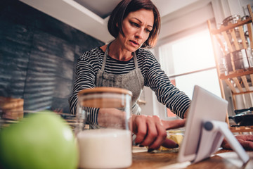 Wall Mural - Woman searching apple pie recipe on the tablet