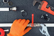 © Sergey - Hands repairing in gloves the plumbing pipes  with a spanner