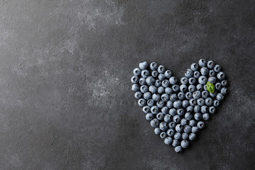 Wall Mural - Fresh blueberries heart shape on black background. Healthy food eating concept.