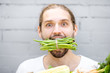 © rh2010 - Close portrait of a handsome man biting green beans on the brick wall background