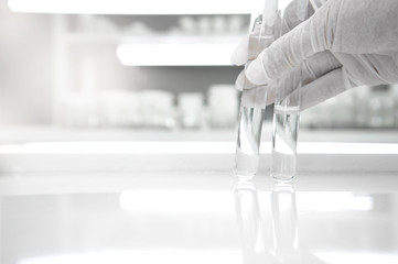 Wall Mural - two of test tube holding by hand of scientist in medical clean white laboratory background