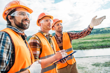 Wall Mural - group of builders in hard hats and reflective vests pointing somewhere