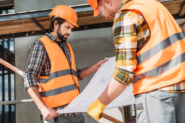 Wall Mural - thoughtful builders with blueprint at construction site