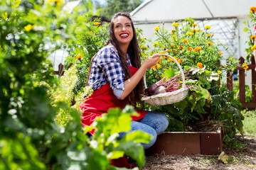 Pretty woman with box of vegetables in her garden