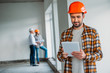 © LIGHTFIELD STUDIOS - handsome architect in plaid shirt and hard hat standing inside of building house and using tablet