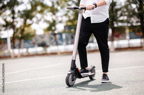 Fotografía Legs of a man in stylish outfit stand on electric scooter on the street