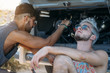 © ADDICTIVE STOCK - Man resting near friend fixing broken car