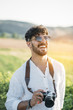 © ADDICTIVE STOCK - Cheerful man with photo camera in nature