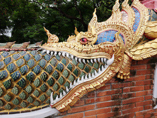 Detail of Naga golden dragon head with big white teeth, ornamental buddhist pattern in buddhist temple in North Thailand