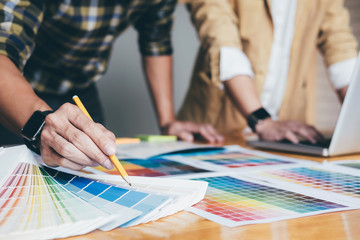 Poster - Young creative team having a meeting in creative office, Architectural drawing with work tools and accessories, Color swatch samples chart for selection coloring