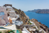 Fototapeta Na drzwi - Tiny little white houses, hotels and long stairway to the harbour in the Oia village at Santorini, Greece.
