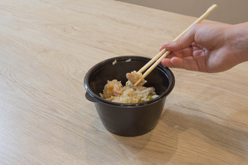 A girl is going to eat in a Chinese  food, they eating with chopsticks, close-up on hands and food