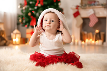 Sticker - Cute baby in Santa hat on floor at home. Christmas celebration