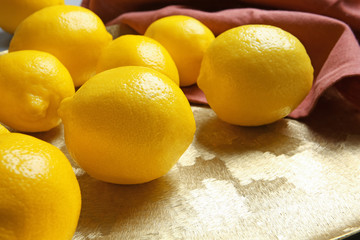 Ripe whole lemons on golden plate, closeup