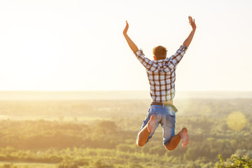 happy guy jumping to the top on the background of nature and sun concept of success and happiness