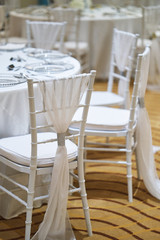 Wall Mural - Back of white chiavari chairs decorated with white sash organza stripe for wedding reception party dinner table