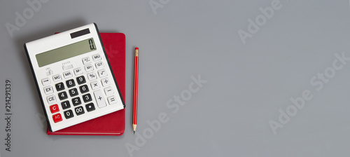 Fotografía white calculator and red organizer on the grey table with red pencil
