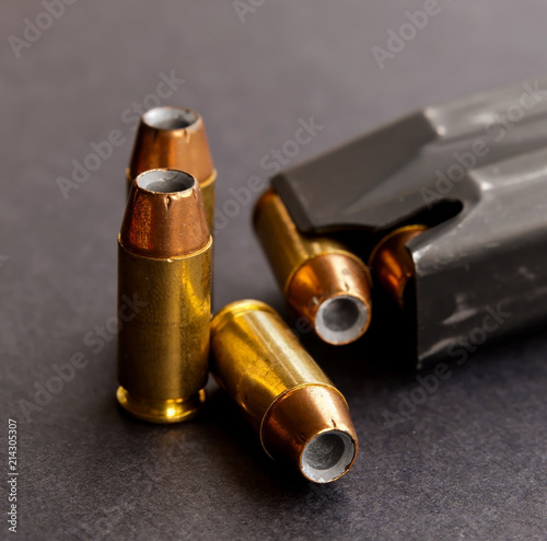 Cuadros en Lienzo Three hollow point bullets next to a loaded pistol magazine on a black backgroun