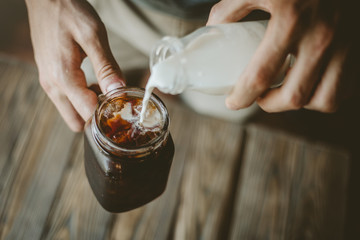 Man pouring milk in iced coffee