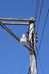 light on telephone pole with power lines and blue sky