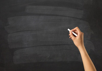 Female hand holding white chalk in front of a blank blackboard
