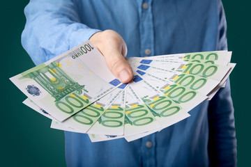 Young businessman holding large amount of bills 