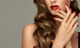 Beautiful girl with long wavy hair . woman with red manicure . girl with bright color nail polish on the nails . Makeup and cosmetics
