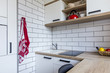 © Michaela Komi - Small tiny white kitchen in panel house in the Czech Republic after the reconstruction with white brick wall and red and oak decoration and oak floor