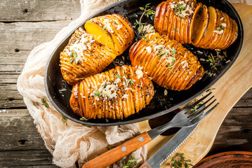 Wall Mural - American traditional home cooking. The vegan diet. Homemade Hasselback Potato with Fresh Herbs and cheese. On old wooden table, copy space