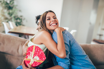 Wall Mural - Man giving a surprise gift to woman at home