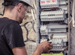 © puhimec - a male electrician works in a switchboard with an electrical connecting cable