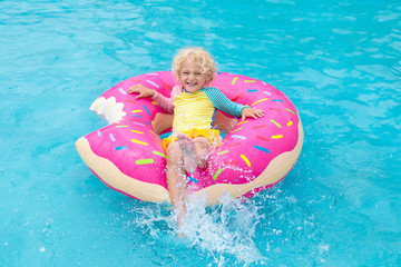 Wall Mural - Child in swimming pool on donut float