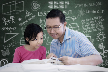 Wall Mural - Little girl learning to read with her teacher