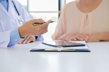  Patient listening intently to a male doctor explaining patient symptoms or asking a question as they discuss paperwork together in a consultation