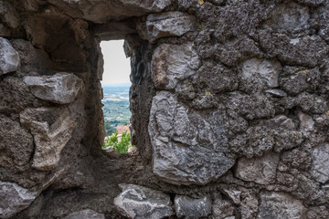 Wallpaper background of landscape view from a hole on an antique stone wall in a medieval town. Sermoneta. Italy. No people.