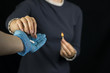 © HENADZY - A girl on a black background holds a burning match, pain and burning sensation in the stomach, a man's hand in a glove holds out to her a pill