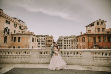 Young newly married couple  posing in Rome with beautiful and ancient architecture in the background