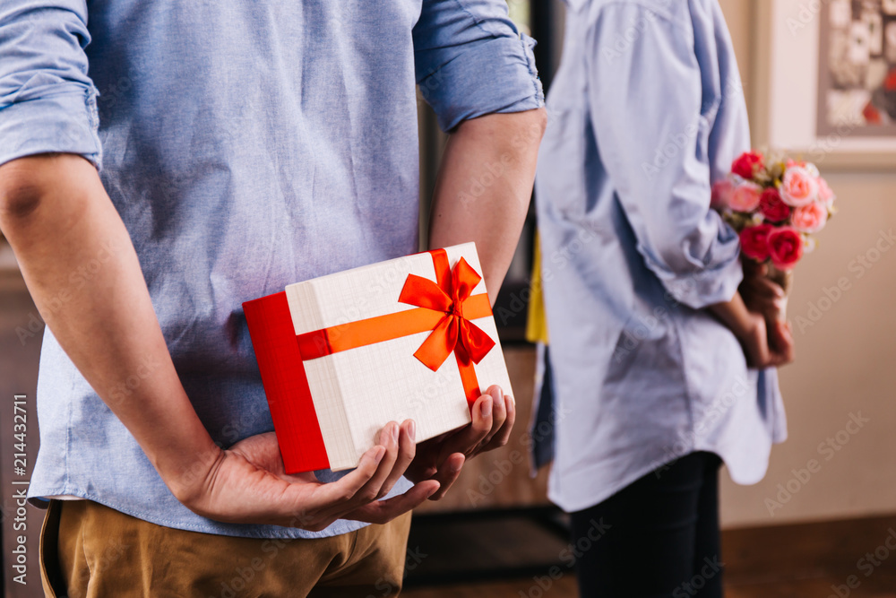 Stock-Foto „Two friends hiding a surprise gift and roses for surprising someone special on special day such as birthday or surprise wedding proposal. Celebration and holiday concept“ | Adobe Stock