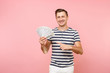 © ViDi Studio - Portrait of smiling excited young man in striped t-shirt holding bundle lots of dollars, cash money, ardor gesture on copy space isolated on pink background. People sincere emotions lifestyle concept.