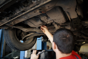 Profecional car mechanic changing motor oil in automobile engine at maintenance repair service station in a car workshop.