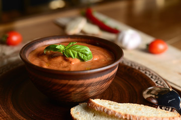 Wall Mural - tomato cream soup with basil on a wooden table