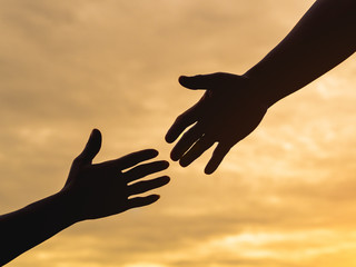 Closeup helping hands on the sunset sky background. Rescue & Help Cencept