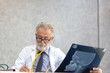 © thbangkok - Senior medical doctor or chief doctor or Surgeon are checking skull of human head via x-ray film In examination room with copy space.