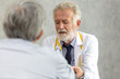 © thbangkok - Senior medical doctor or chief doctor giving a consultation to her male patient and explaining medical informations and diagnosis at the clinic or hospital.