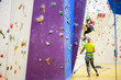 Photo of young girl exercising on climbing wall with trainer