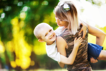 Portrait of happy child hugging mom outdoors at summer park.