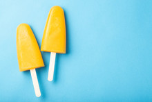 Orange popsicles with juice on a blue bacground. Ice pops, flat lay, top view with copy space