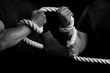 Men tighten a rope on a black background